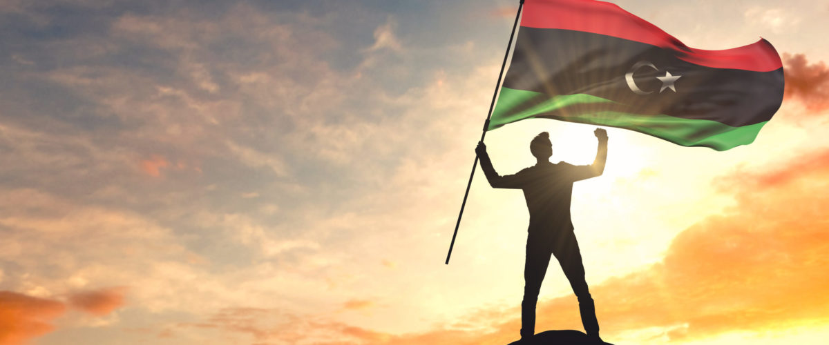 Libya flag being waved by a man celebrating success at the top of a mountain. 3D Rendering